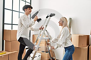 Man going up ladder holding drill at new home