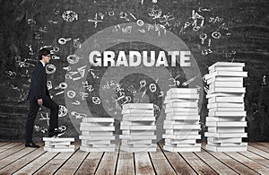 A man is going up using a stairs which are made of white books. The word graduate is on the black chalkboard.