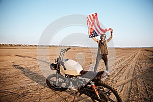 Man in golden helmet waving american flag at the desert