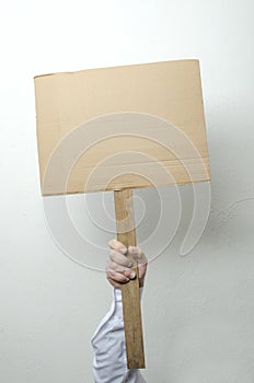 Man golding empty cardboard against white wall. Concept of strike , work stoppage. Template for strike and labor slogans