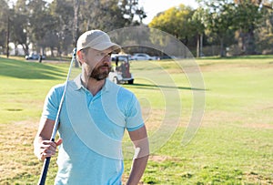 man golfer in cap with golf club on summer green grass, sport