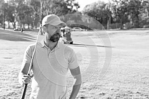 man golfer in cap with golf club on summer green grass, sport