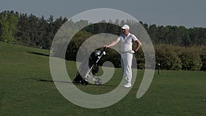 Man golfer carrying bag and walking to next hole at golf course