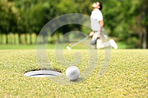 Man golfer cheering after a golf ball on a golf green