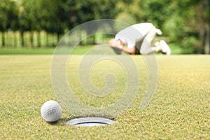 Man golfer feeling disappointed after a putted golf ball missed the hole