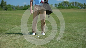Man golfer putting sport equipment bag on green, taking club and ready to play