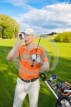 Man golfer watching into rangefinder
