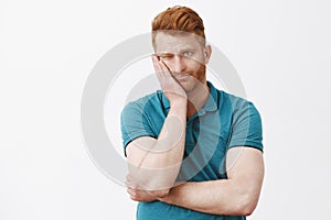 Man got stucked on parents meeting in school, feeling bored and uninterested. Gloomy indifferent redhead guy with photo