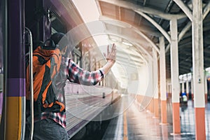 A man grabbed the handrail of the train door and waved his hand. People travel by local transport