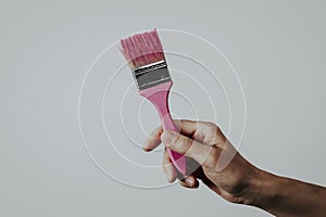 Man grabbing a paintbrush with pink paint