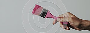 Man grabs a paintbrush with pink paint, banner