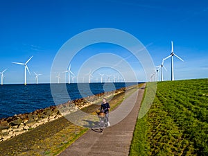 A man gracefully rides a bike down a picturesque path next to windmill turbines in Spring