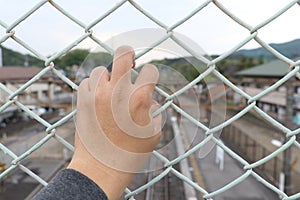 Man grasp the bar of cage with the defocus of city background