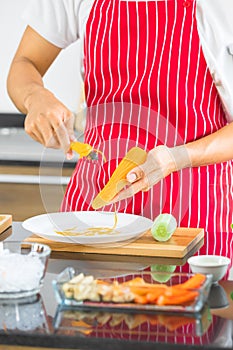 Man grates the carrot into strips, in kitchen