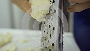 A man grates cauliflower on a metal grater.