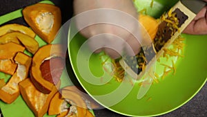 A man grates slices of orange pumpkin. Close-up shot from above
