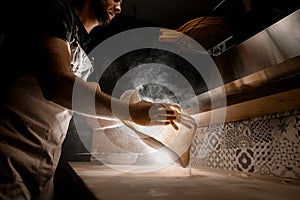 Man in gray apron making a pizza dough on a table before preparing a pizza
