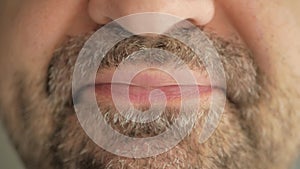 A man with a gray beard swallows a pill from the virus, coronavirus, and makes a wry face. Super macro close-up.