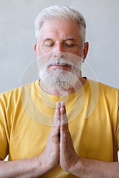 man with gray hair meditates and does breathing exercises. sports fitness and physical exercises for the elderly