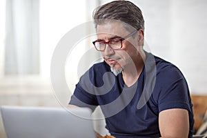 Man with gray hair using laptop at home