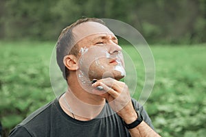 Man in a gray shaves outdoors
