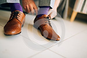 The man in gray slacks and a purple dress socks brown shoes with