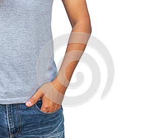 man in a gray T shirt and denims holds his hands in pockets on whitebackground