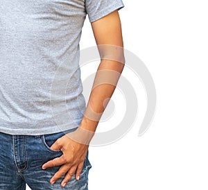 man in a gray T shirt and denims holds his hands in pockets on whitebackground