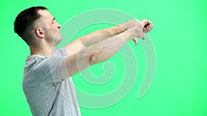 A man in a gray T-shirt, on a green background, close-up, shows his thumbs down