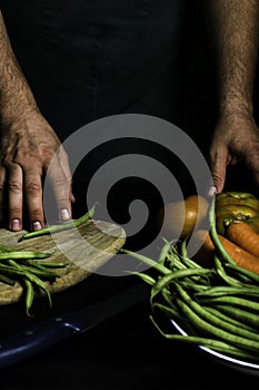 Man with green apron presenting vegetables and garden vegetables