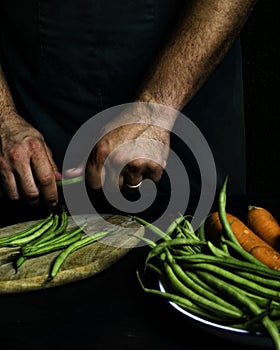 Man with green apron presenting vegetables and garden vegetables