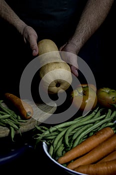 Man with green apron presenting vegetables and garden vegetables