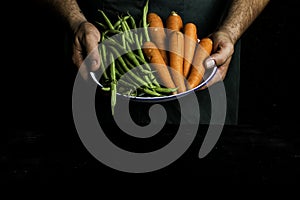 Man with green apron presenting vegetables and garden vegetables