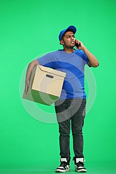 A man on a green background with box conversate on the phone