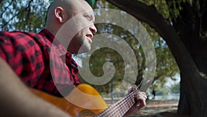 A man with a green mohawk playing guitar and singing at park