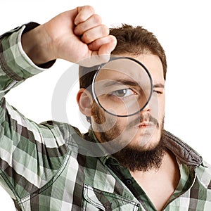 Man in green shirt looking through a magnifying glass.