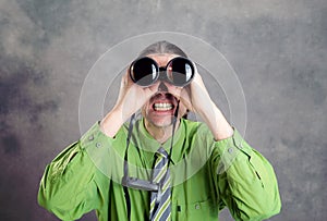 Man in green shirt and necktie looking through a binoculars