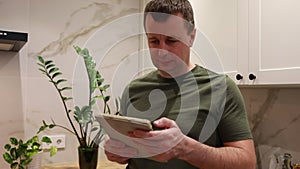Man in a Green Shirt Using Tablet in a Modern Kitchen Setting