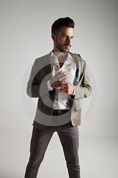 Man in green suit fixing his cuffs looks to side