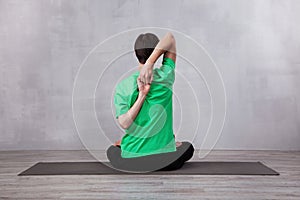 Man in green t-shirt doing yoga exercise. Back hands lock