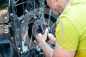 A man in a green t-shirt removes the door card to find a problem in the inoperative power window and repair it photo