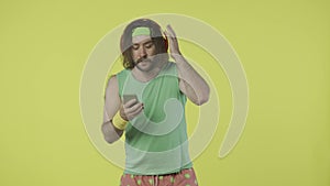 Man in green top and headband with smartphone and headphones picks music in the app and starts running. Isolated on