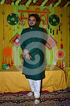 Man in green tunic next to table with orange decor in a Mehndi Ceremony