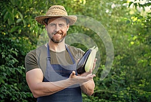 man greengrocer presenting eggplant and vegetable marrow