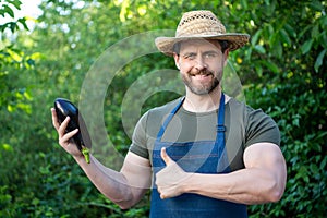 man greengrocer in straw hat with eggplant vegetable. thumb up