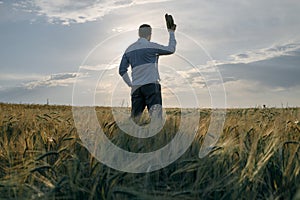 A man greets the dawn on the field with his hat raised in greeting