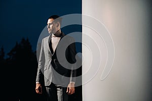 A man in a grey business suit stands next to a windmill after sunset .Businessman near windmills at night.Modern concept of the