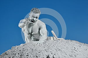 Man among grey sand screaming and showing by hand.