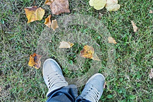 Man with grey sneakers at green grass looking at his shoes