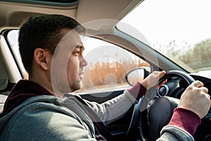 Man in grey sweater behind wheel of car.  reeds